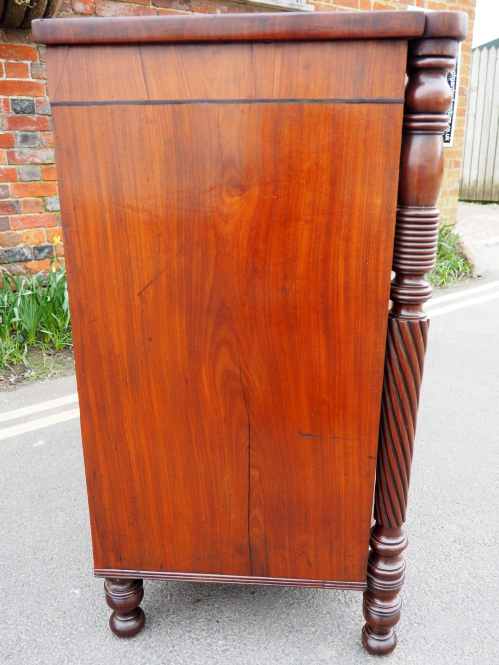 A Regency period mahogany bowfront chest of drawers featuring three full-width drawers, spiral-turned side columns, and circular brass handles. View XV