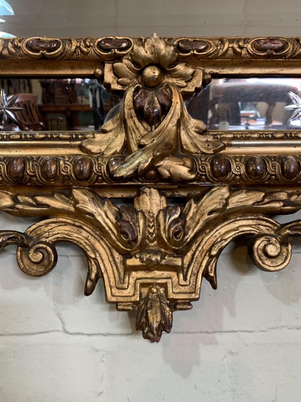 A nineteenth-century rectangular giltwood wall mirror featuring a carved crest with a sculpted mask, winged creatures, and star-etched border panels. View III
