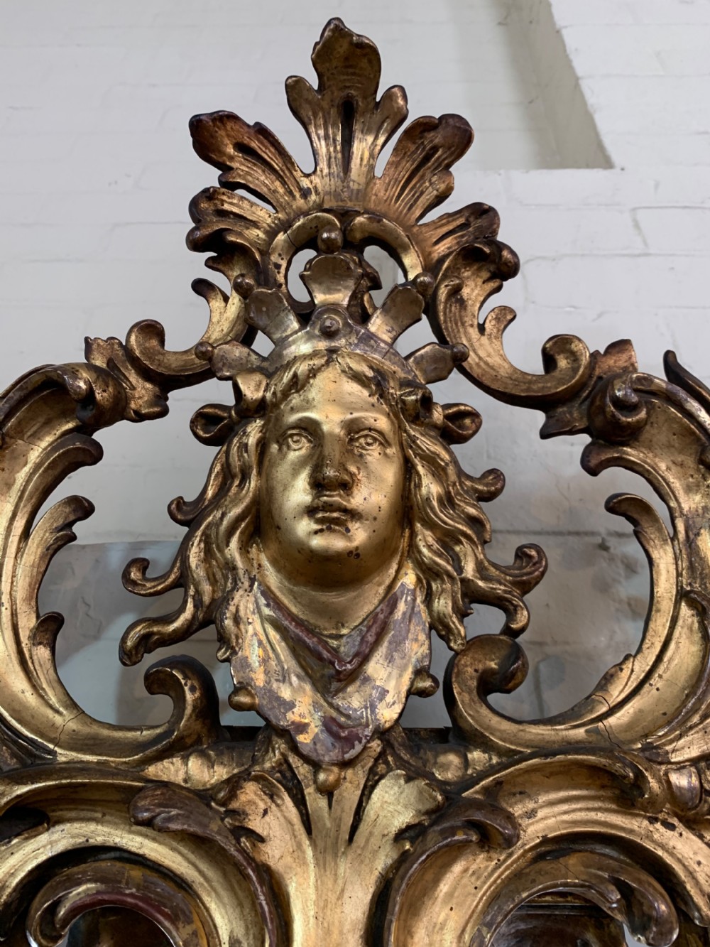 A nineteenth-century rectangular giltwood wall mirror featuring a carved crest with a sculpted mask, winged creatures, and star-etched border panels. View VI