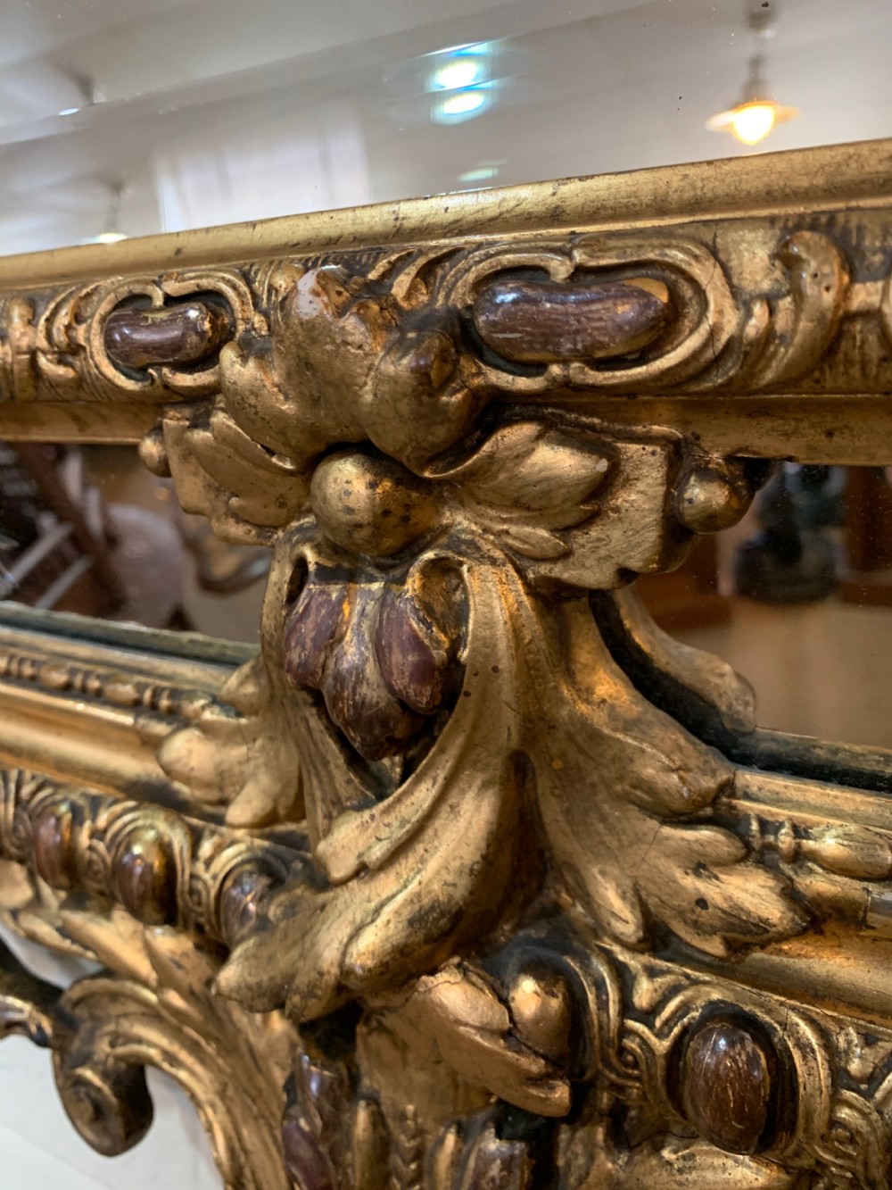 A nineteenth-century rectangular giltwood wall mirror featuring a carved crest with a sculpted mask, winged creatures, and star-etched border panels. View VII