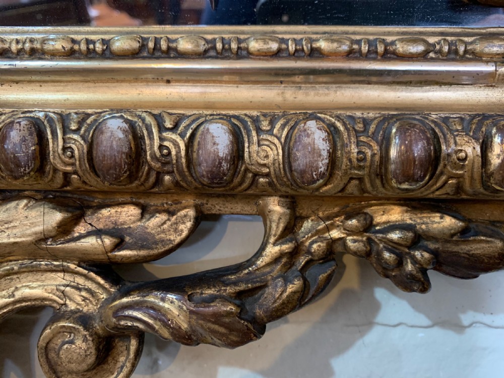 A nineteenth-century rectangular giltwood wall mirror featuring a carved crest with a sculpted mask, winged creatures, and star-etched border panels. View XII