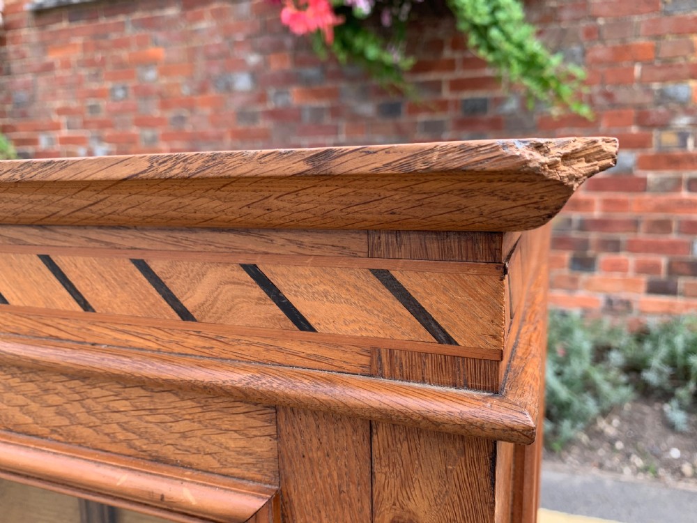 A low three-door oak vestry cupboard featuring clear glass panels, incised frieze carving, and bun feet. View III