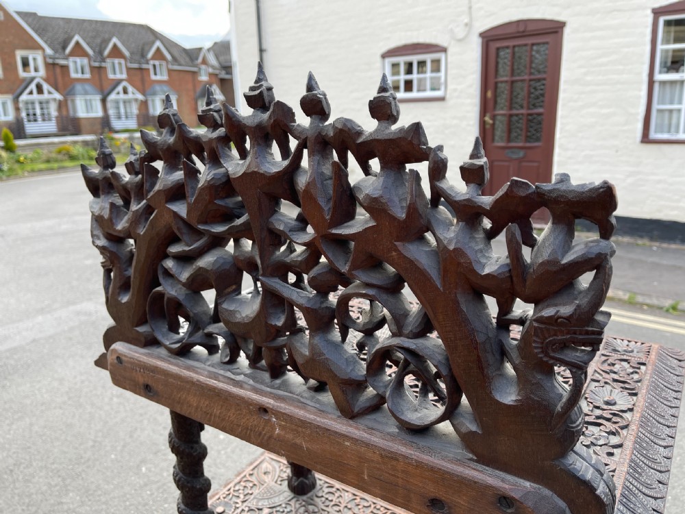 A three-tier dark teak carved whatnot featuring spiralled support posts and a deeply carved mythological cresting gallery at the top. View VII