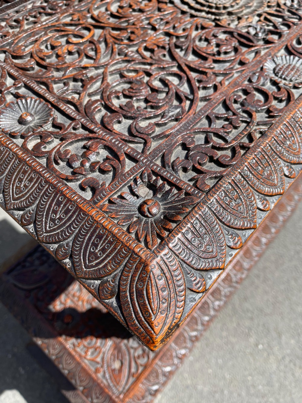 A three-tier dark teak carved whatnot featuring spiralled support posts and a deeply carved mythological cresting gallery at the top. View IX