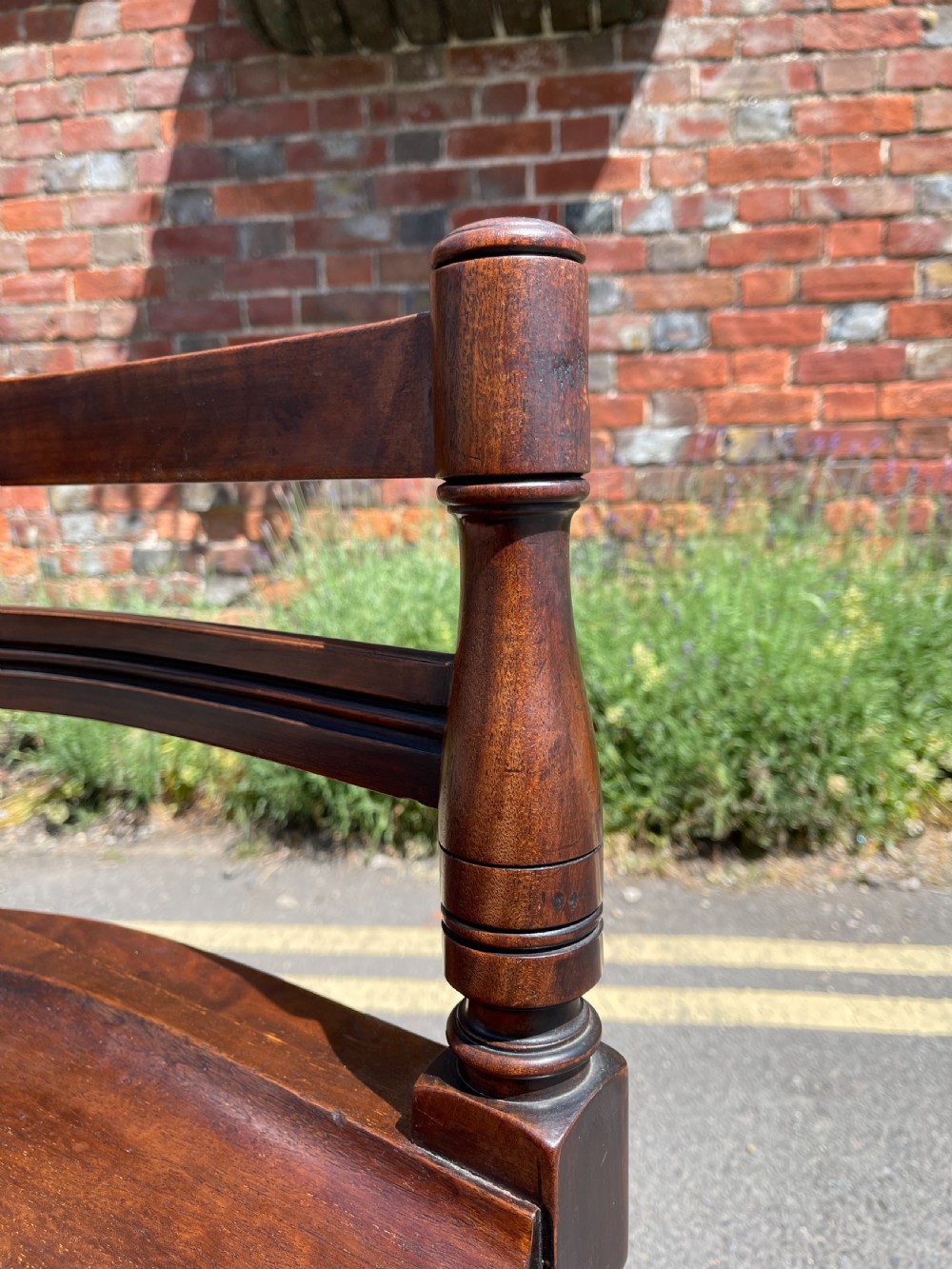 A dark brown wood revolving desk chair featuring a curved slatted backrest, turned arm posts, a contoured seat, and four splayed legs with brass castors. View II