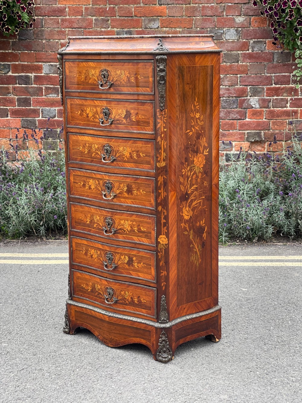 A tall, narrow 19th-century French rosewood semainier chest featuring seven drawers with floral marquetry inlay, bronze handles, and a marble top.