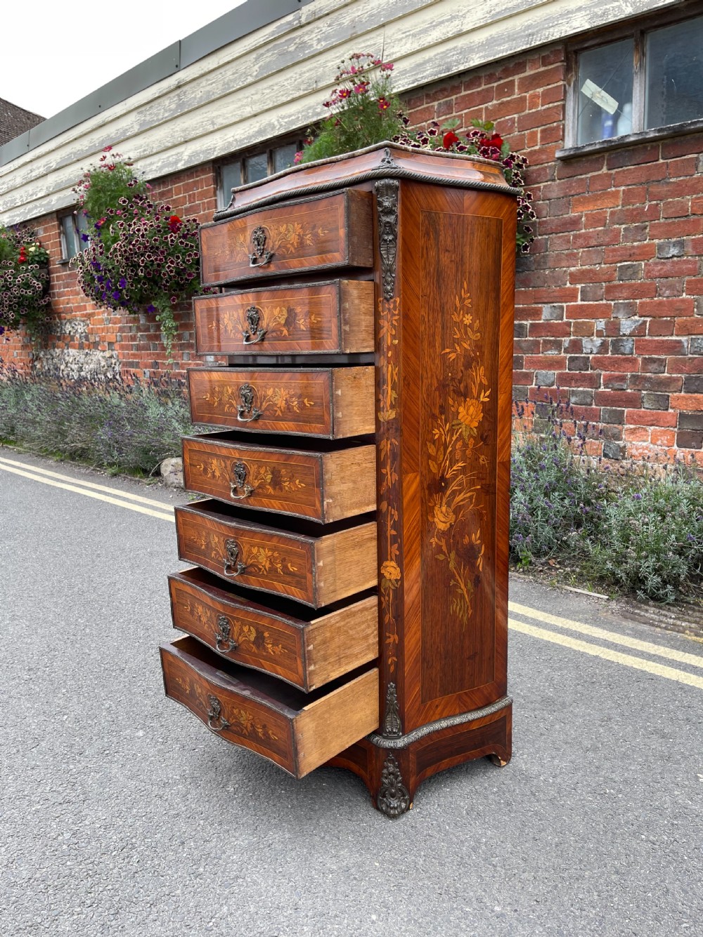 A tall, narrow 19th-century French rosewood semainier chest featuring seven drawers with floral marquetry inlay, bronze handles, and a marble top. View IX