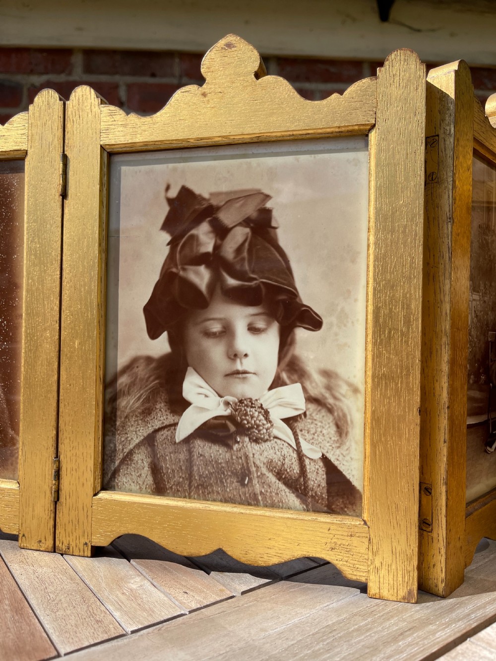 An Edwardian six-fold giltwood photo frame featuring shaped top crests and monochrome portrait photographs. View III