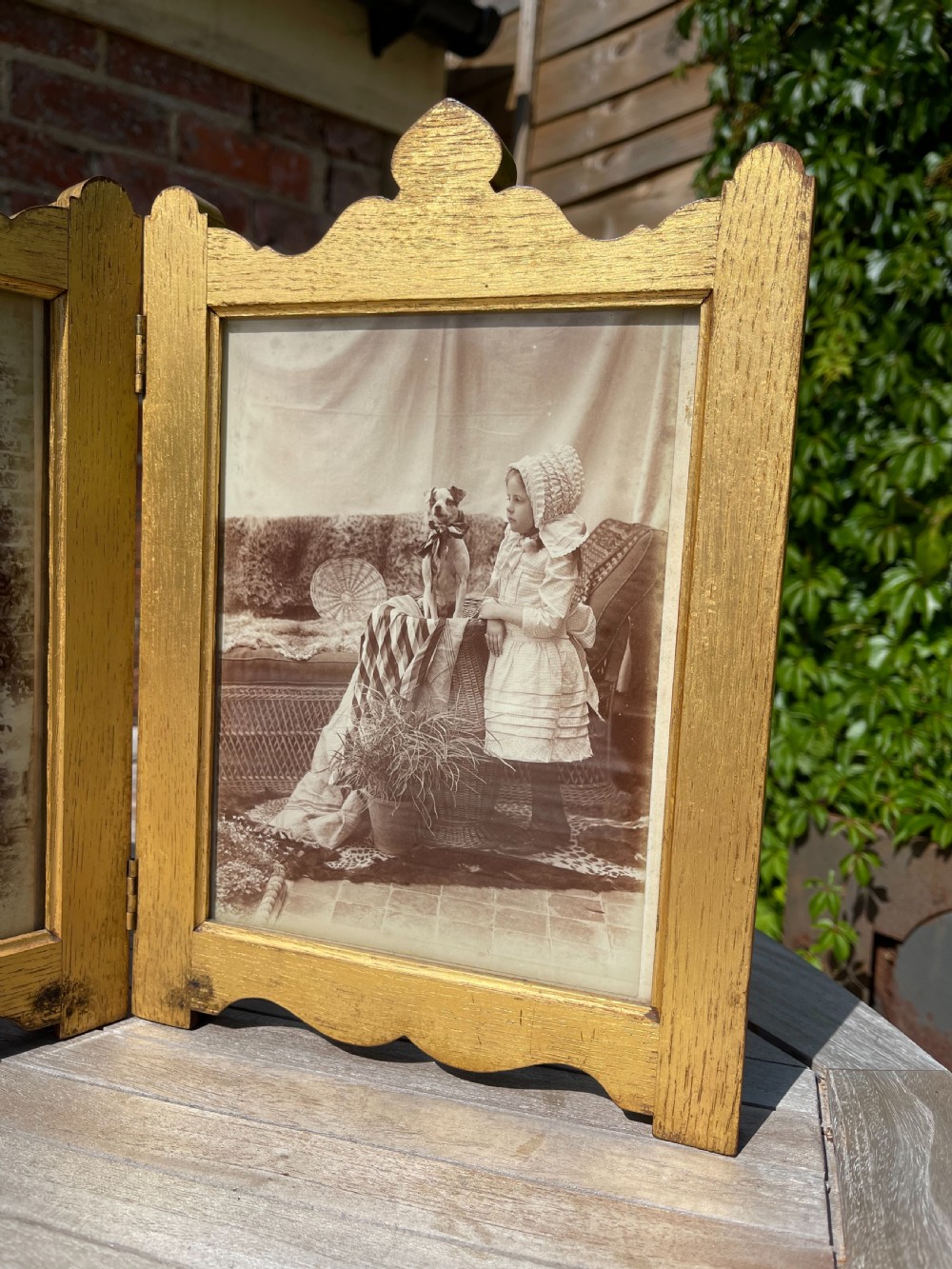 An Edwardian six-fold giltwood photo frame featuring shaped top crests and monochrome portrait photographs. View IV