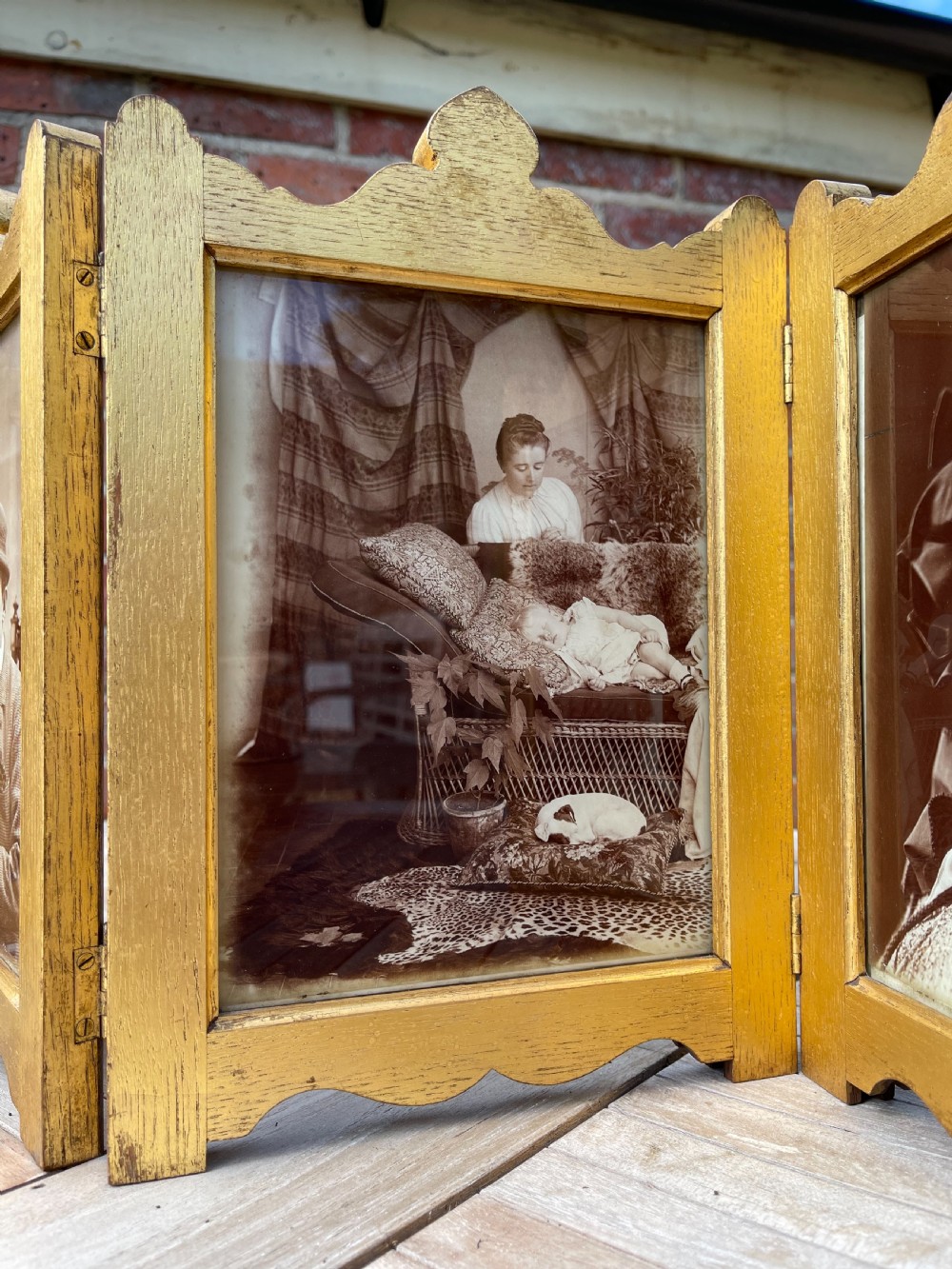 An Edwardian six-fold giltwood photo frame featuring shaped top crests and monochrome portrait photographs. View V