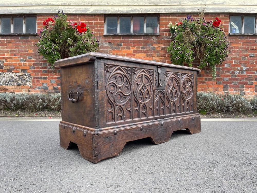 An eighteenth century Continental chestnut coffer featuring hand-carved gothic tracery panels and wrought iron carrying handles.