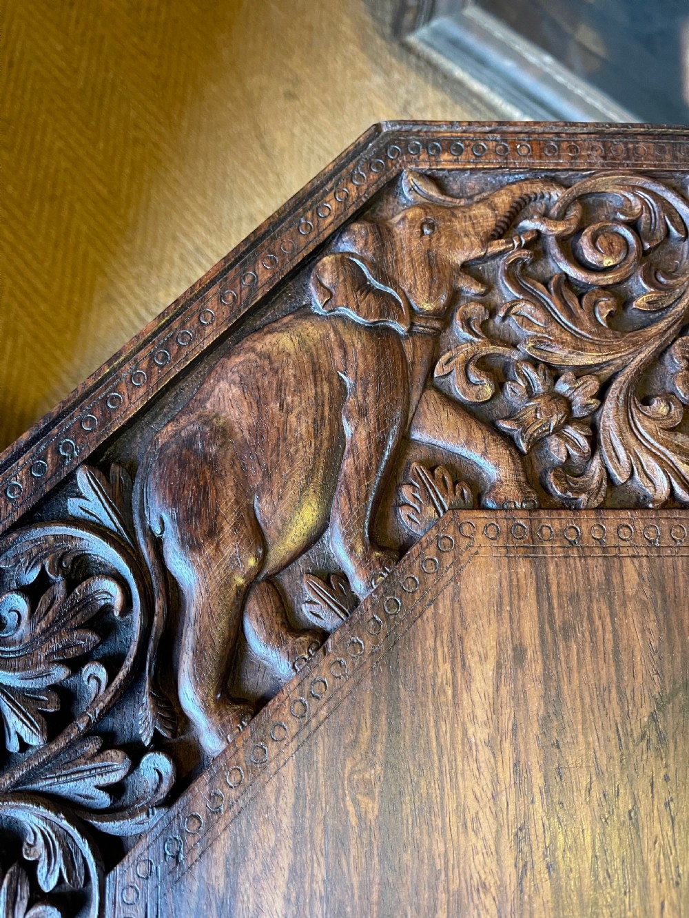 A hand-carved dark wood octagonal side table featuring carved elephant head legs with bone tusks and a floral border. View IV