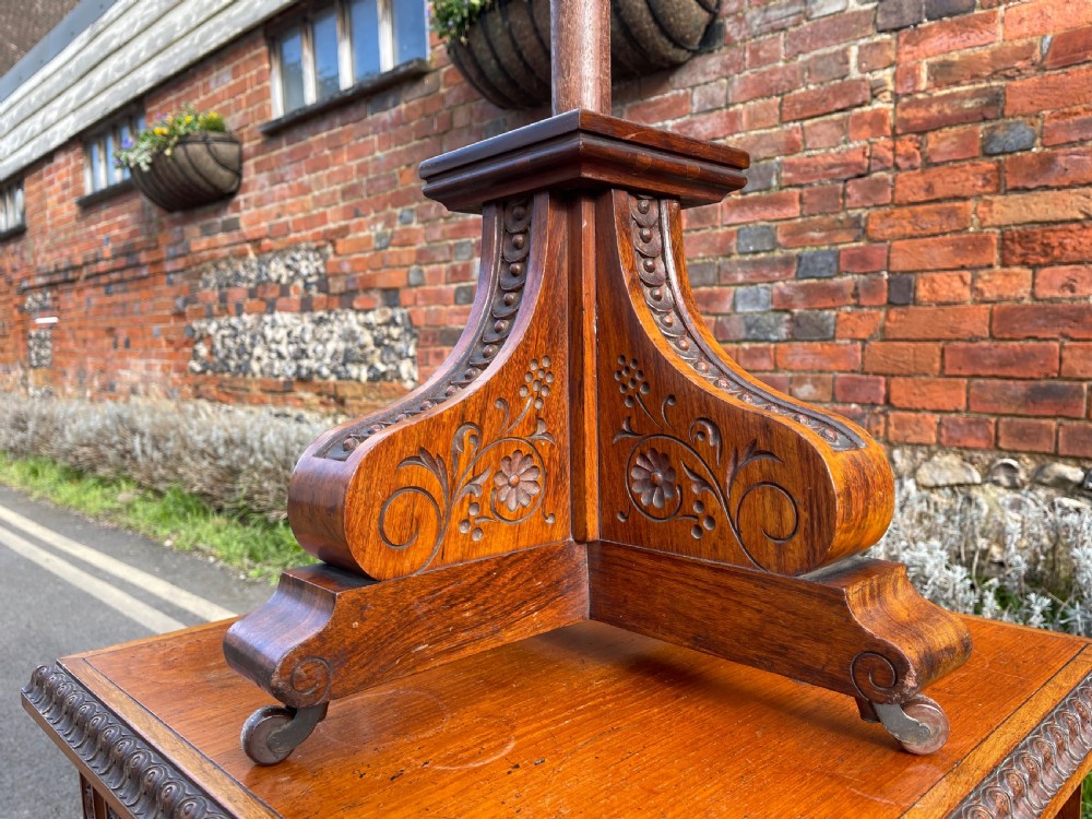 An Anglo-Indian carved wood revolving bookcase featuring vertical foliate slats and a tiered pedestal base. View II