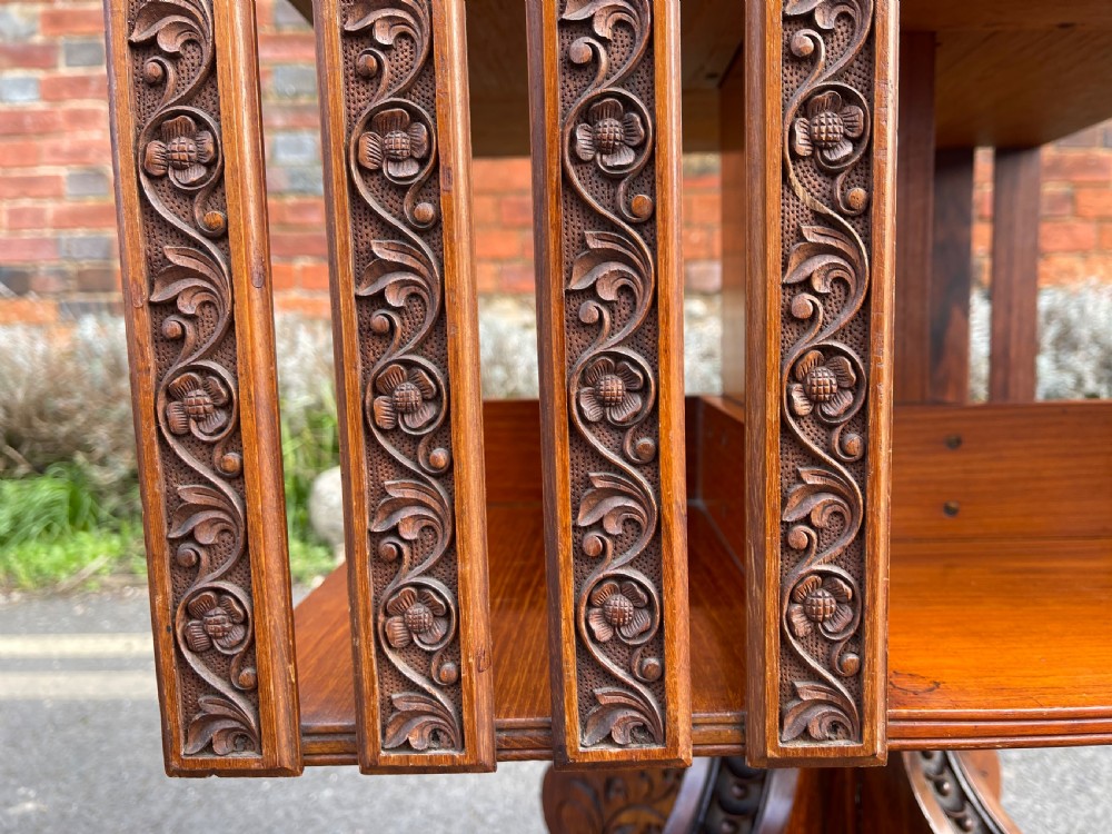 An Anglo-Indian carved wood revolving bookcase featuring vertical foliate slats and a tiered pedestal base. View IX
