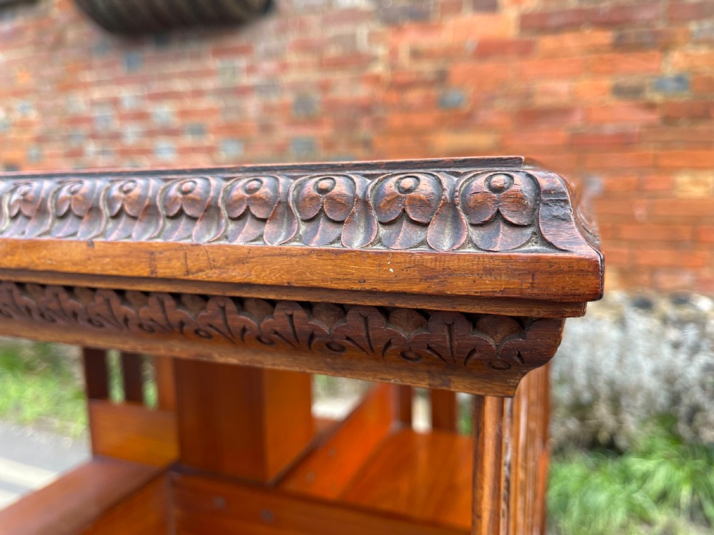 An Anglo-Indian carved wood revolving bookcase featuring vertical foliate slats and a tiered pedestal base. View X