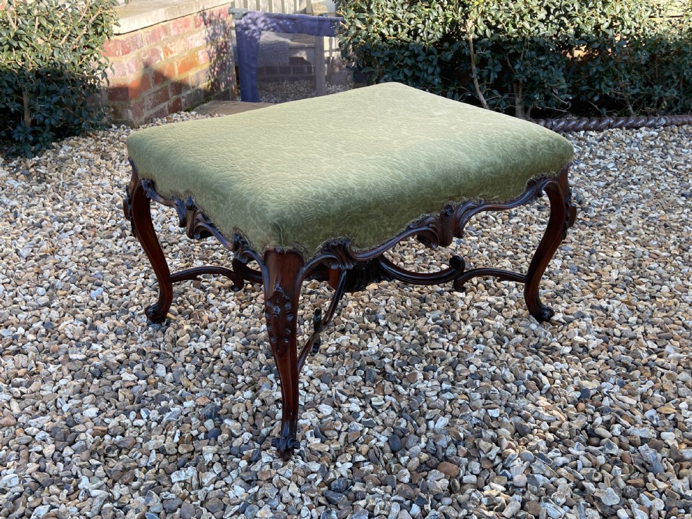 A nineteenth-century rosewood footstool featuring carved cabriole legs and a textured green fabric upholstered top.