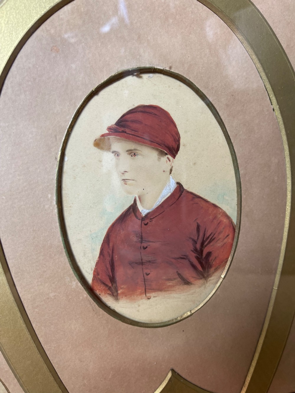 A pair of dark wood framed prints displaying miniature jockey portraits arranged inside gilded horseshoe-shaped matting. View III