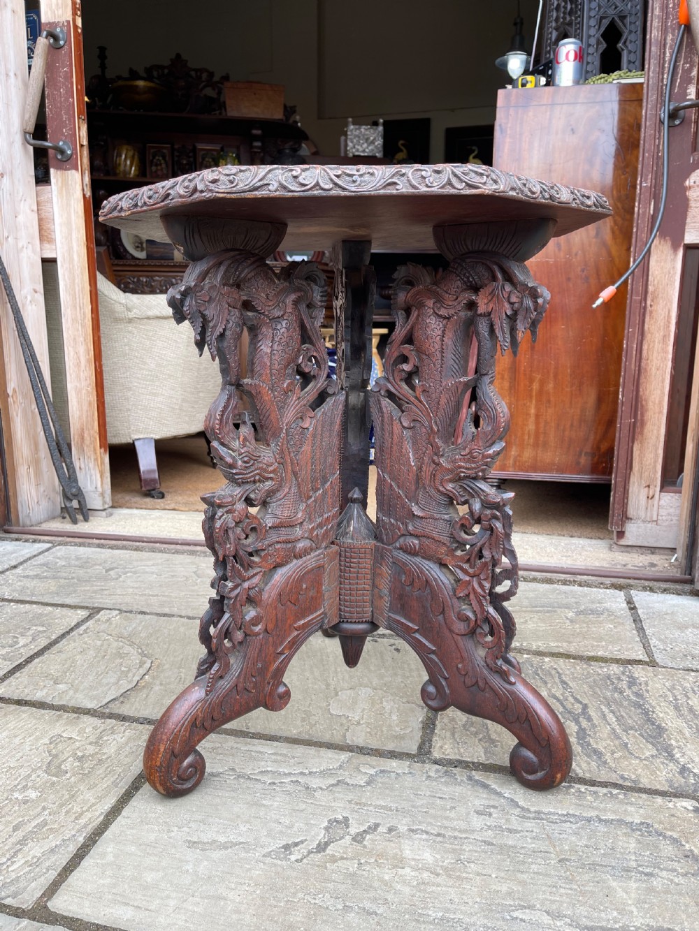 A nineteenth-century octagonal Burmese teak side table featuring intricately carved floral borders and openwork carved legs with mythical animal motifs. View III