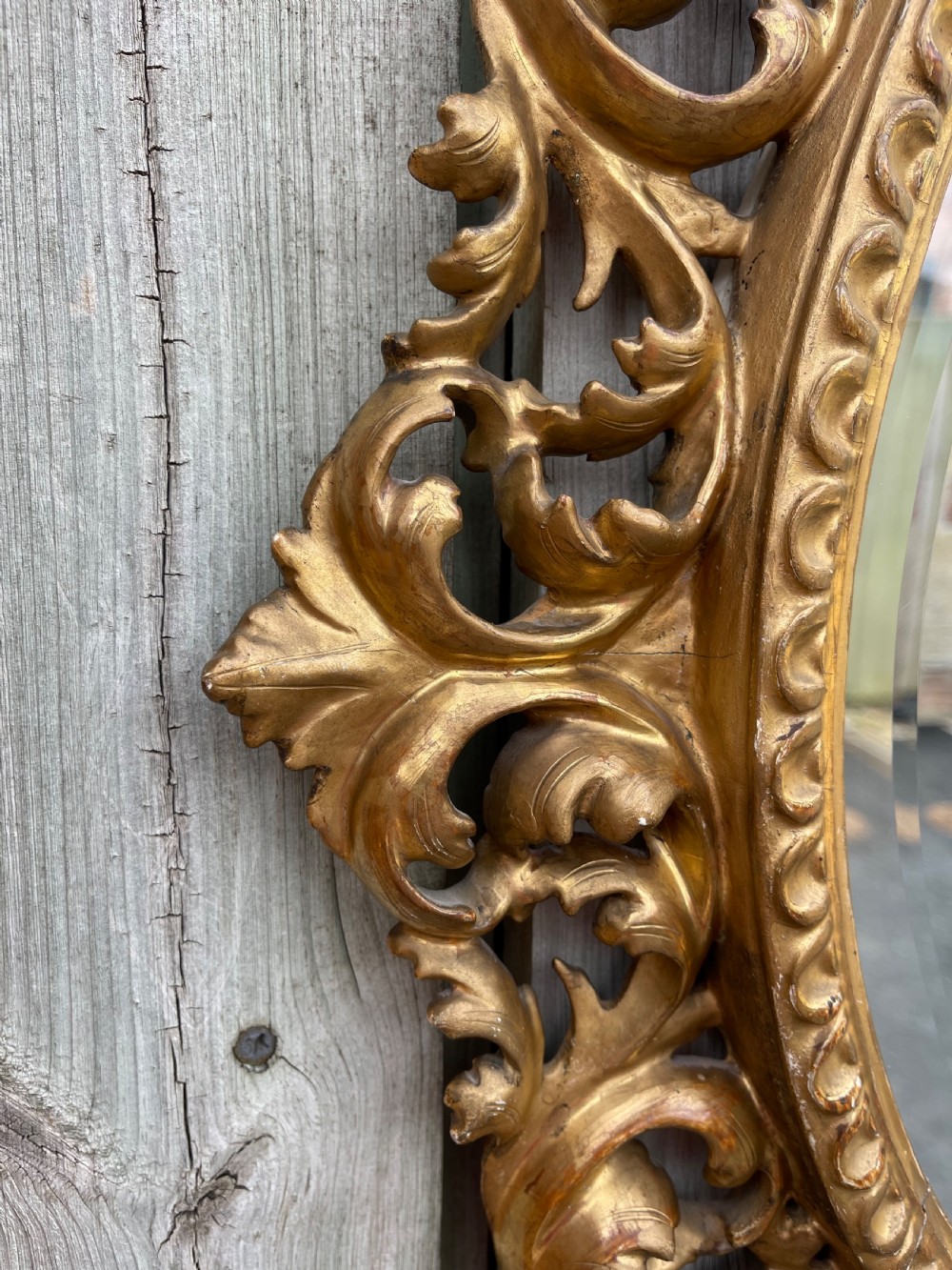 A matching pair of circular wall mirrors featuring elaborate carved giltwood frames decorated with scrollwork and shell motifs. View II