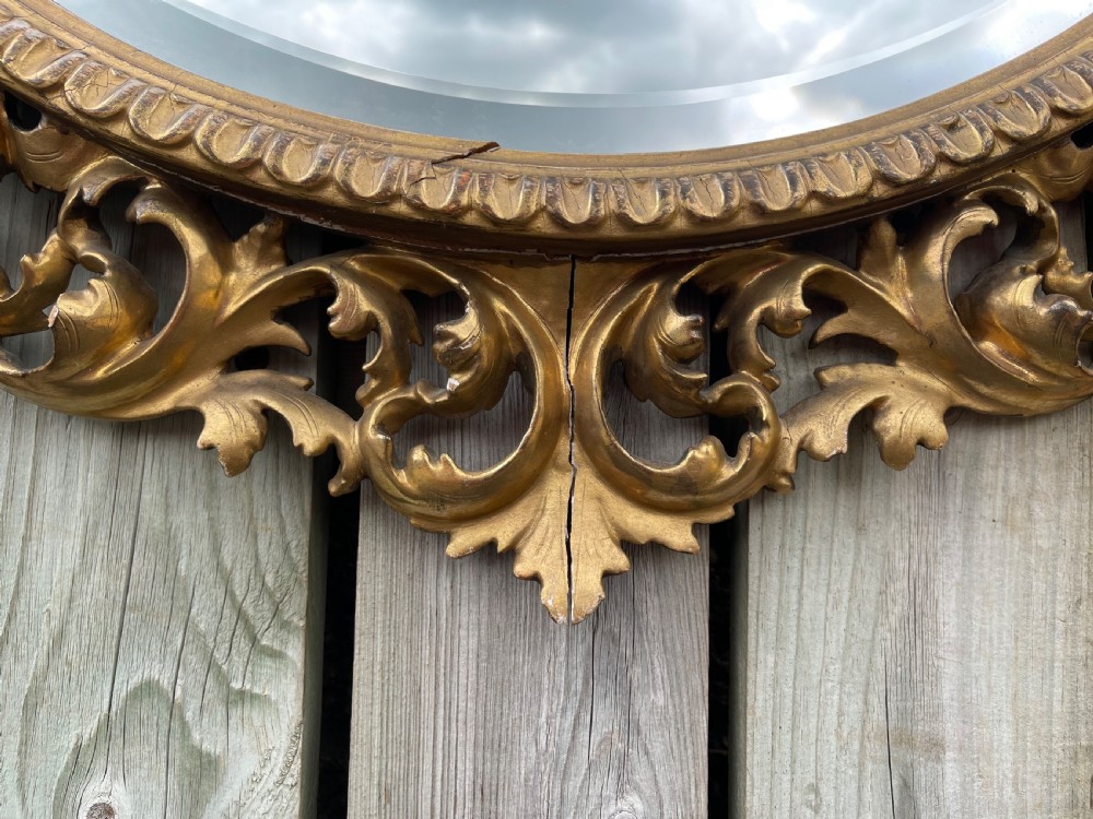 A matching pair of circular wall mirrors featuring elaborate carved giltwood frames decorated with scrollwork and shell motifs. View III