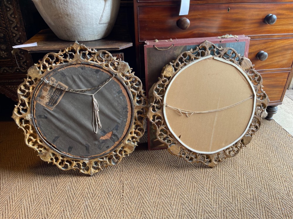 A matching pair of circular wall mirrors featuring elaborate carved giltwood frames decorated with scrollwork and shell motifs. View V