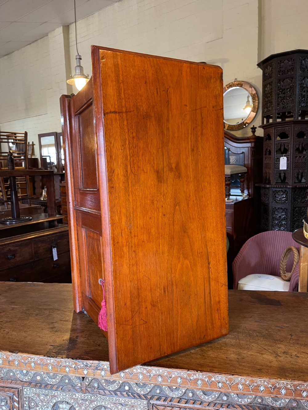 An antique warm brown oak desktop filing cabinet featuring panelled doors and small index drawers with oval metal pulls. View VIII
