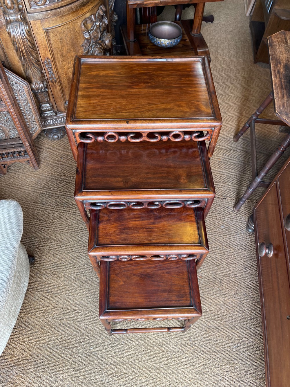 A set of four graduated dark hardwood nesting tables featuring pierced openwork aprons and bamboo-form carved legs. View II