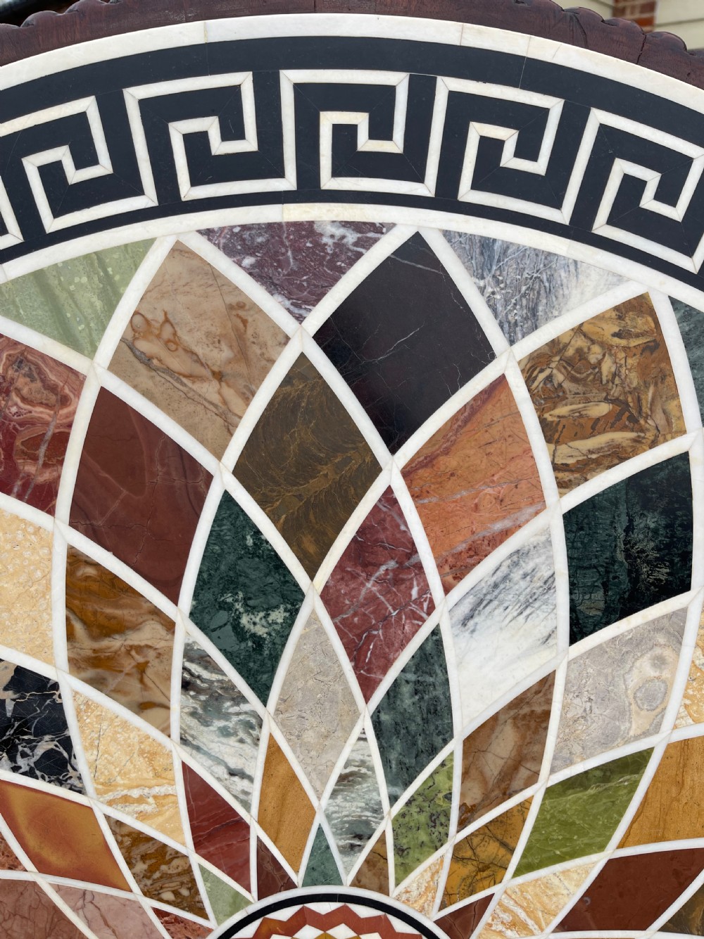 A circular nineteenth-century mahogany centre table featuring a geometric specimen marble mosaic top bordered by a Greek key pattern, supported by a carved pedestal base. View IV