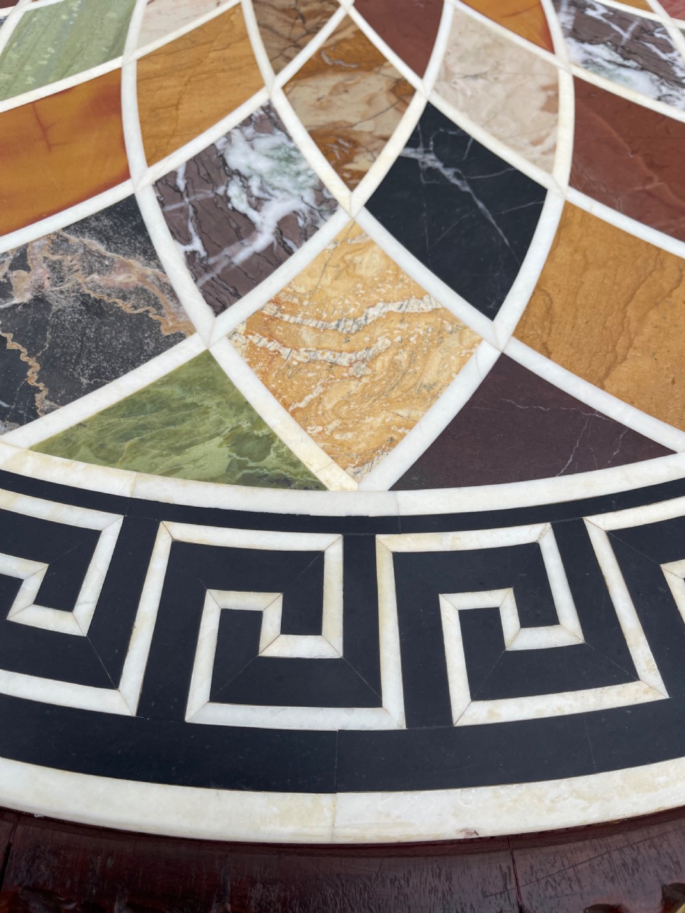 A circular nineteenth-century mahogany centre table featuring a geometric specimen marble mosaic top bordered by a Greek key pattern, supported by a carved pedestal base. View X