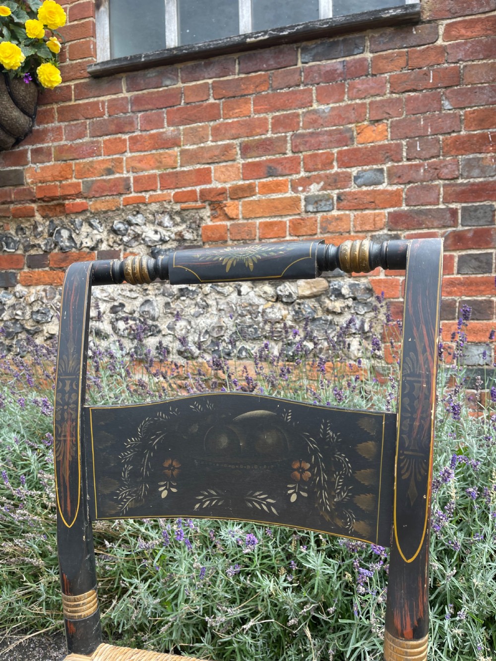 A set of four black-painted wooden side chairs featuring gold stencilled foliage, turned legs, horizontal back slats, and rush seats. View II