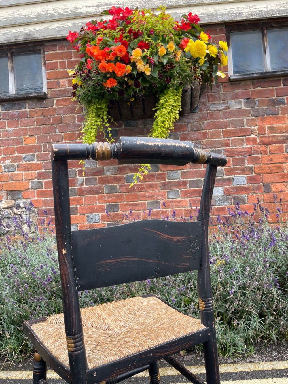 A set of four black-painted wooden side chairs featuring gold stencilled foliage, turned legs, horizontal back slats, and rush seats. View III