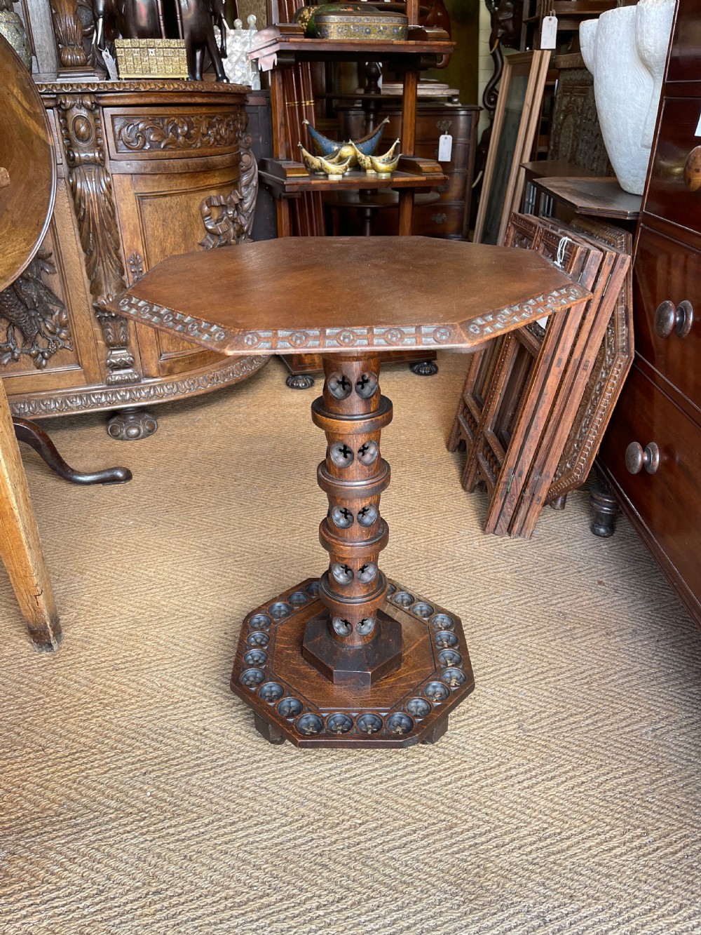 A nineteenth-century dark oak octagonal occasional table featuring a central turned column with carved quatrefoil piercings and a geometric carved base.