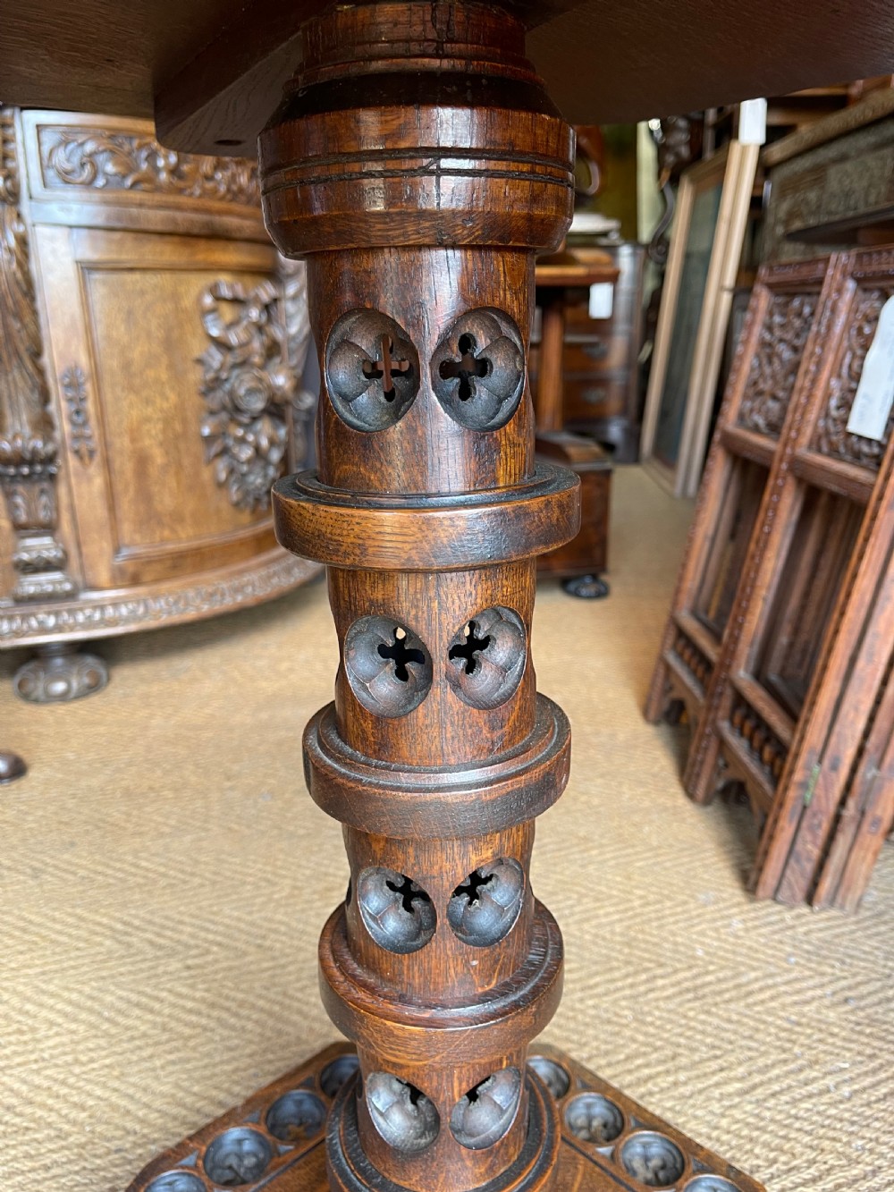 A nineteenth-century dark oak octagonal occasional table featuring a central turned column with carved quatrefoil piercings and a geometric carved base. View III