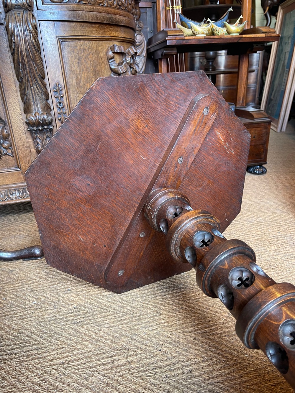 A nineteenth-century dark oak octagonal occasional table featuring a central turned column with carved quatrefoil piercings and a geometric carved base. View VIII