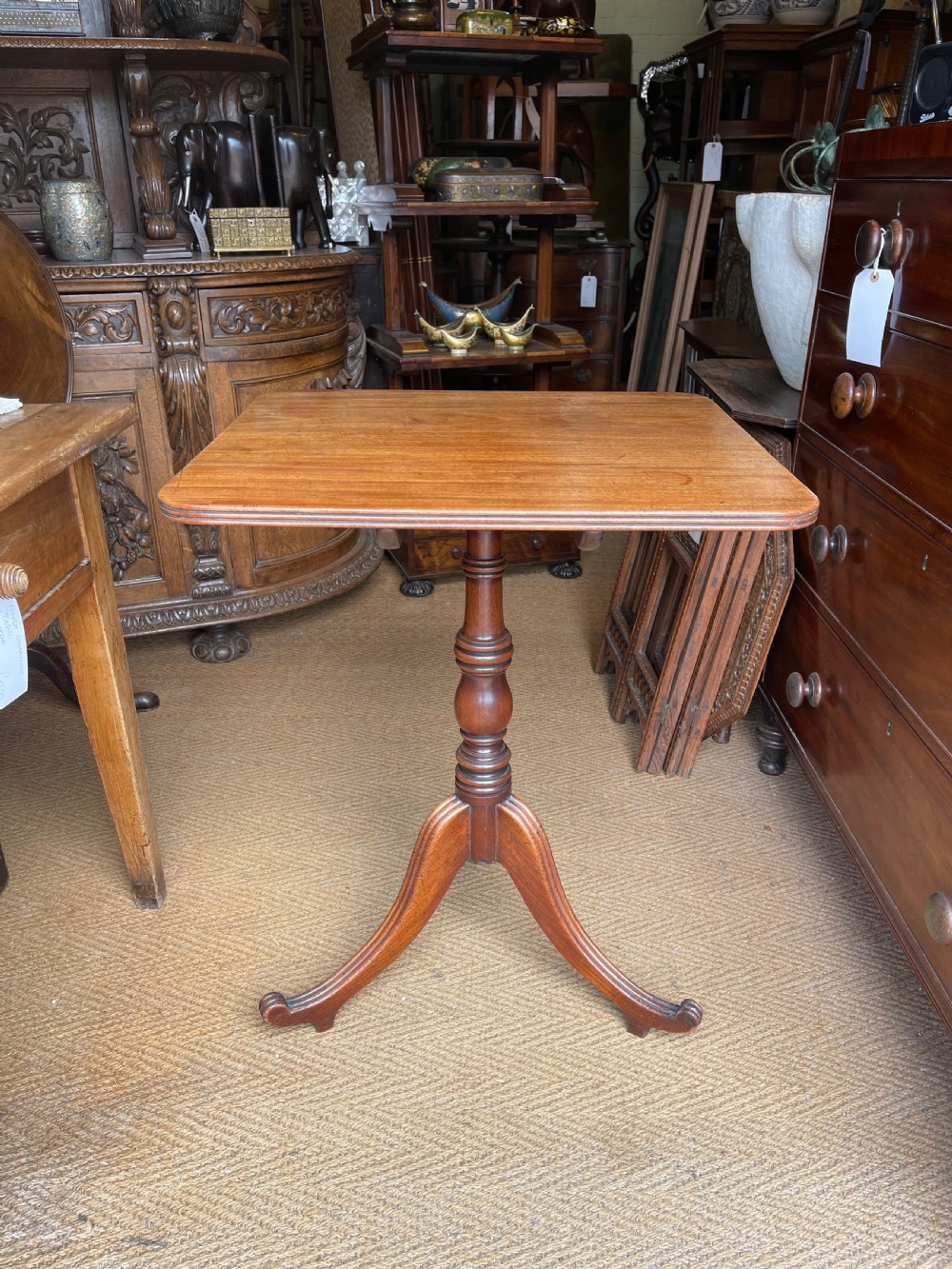 A Georgian mahogany tilt top table displayed vertically, featuring a rectangular top, turned central column, and reeded tripod legs. View II