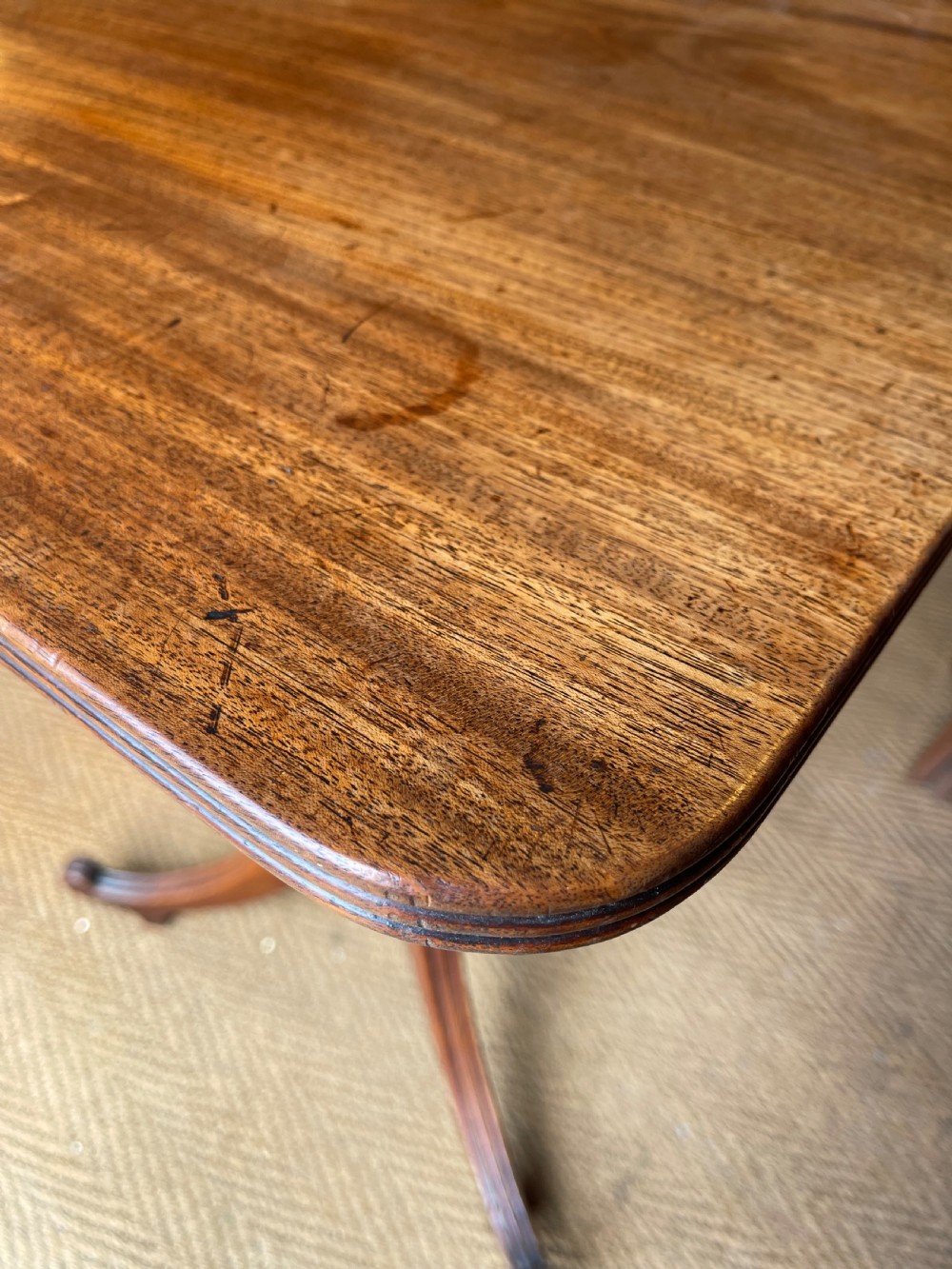 A Georgian mahogany tilt top table displayed vertically, featuring a rectangular top, turned central column, and reeded tripod legs. View V
