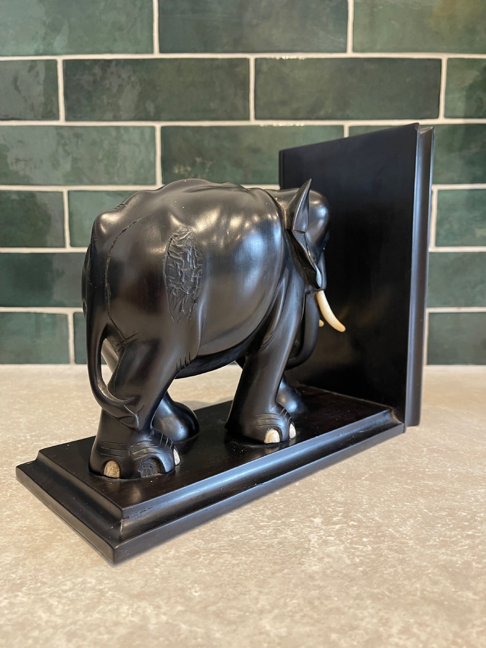 A pair of dark carved wooden elephant bookends with bone tusks on rectangular bases. View III