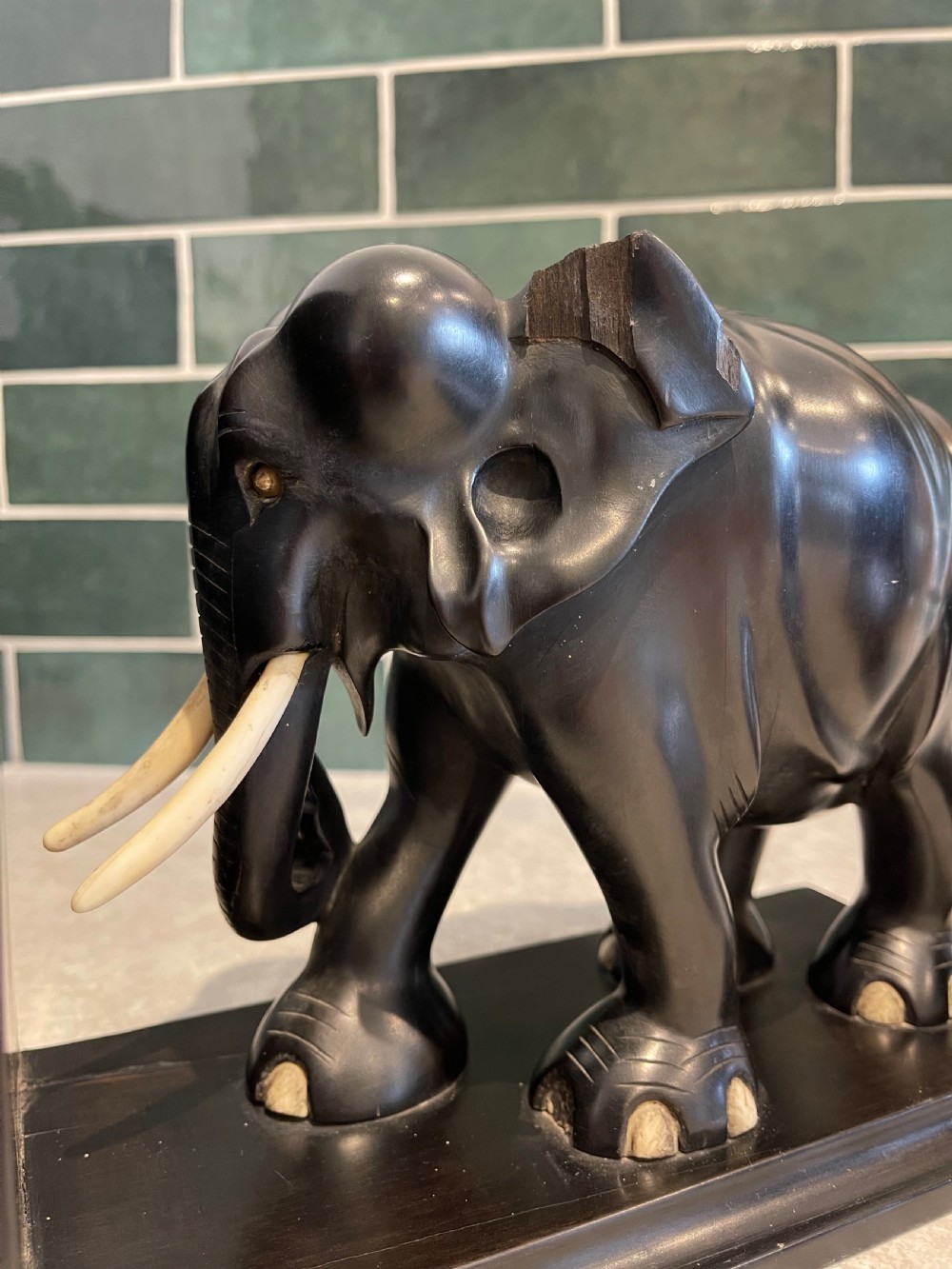 A pair of dark carved wooden elephant bookends with bone tusks on rectangular bases. View V