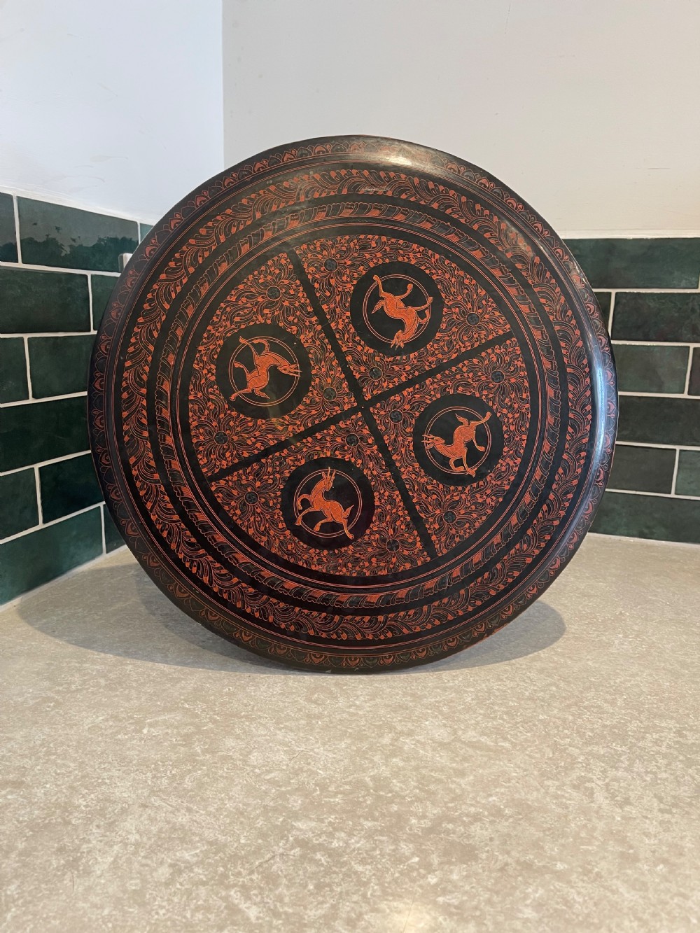 An octagonal Burmese lacquered folding side table featuring black and red panels decorated with incised geometric and floral motifs above arched openwork legs. View III