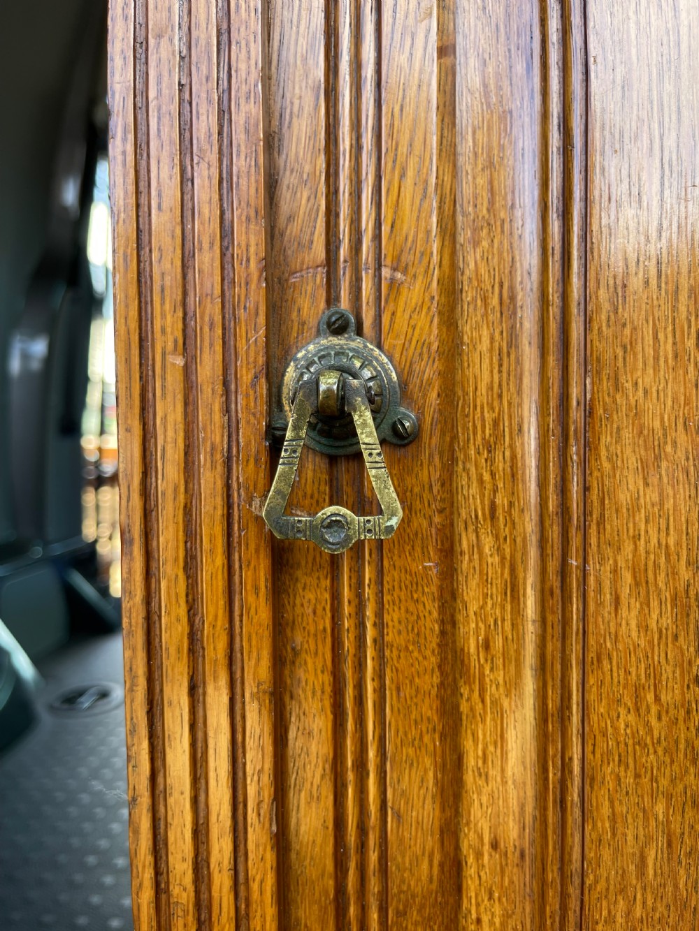 A late Victorian oak bedside cupboard featuring a turned spindle gallery top and a fielded panel single door with a brass handle. View II