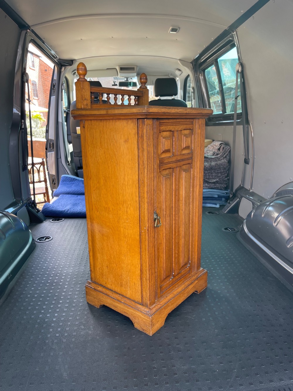 A late Victorian oak bedside cupboard featuring a turned spindle gallery top and a fielded panel single door with a brass handle. View III