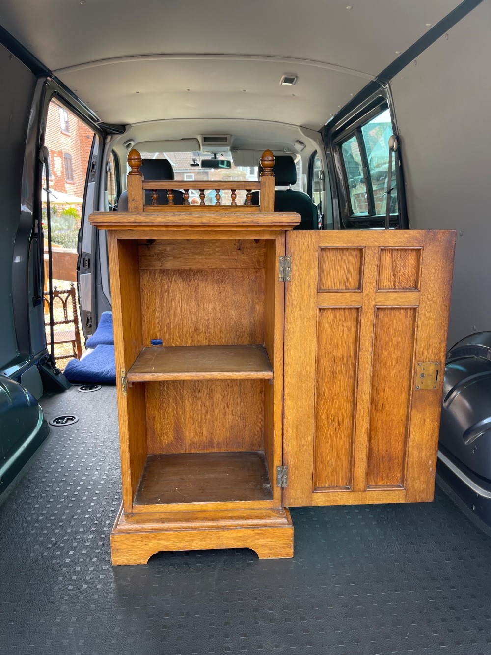 A late Victorian oak bedside cupboard featuring a turned spindle gallery top and a fielded panel single door with a brass handle. View V