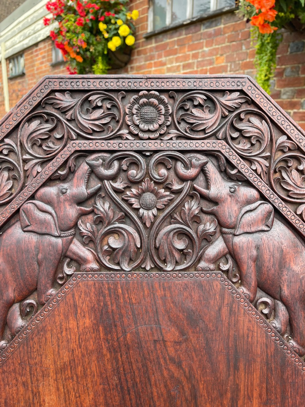 A dark brown carved wood occasional table featuring an octagonal top and three legs sculpted into detailed elephant heads with light tusks. View II