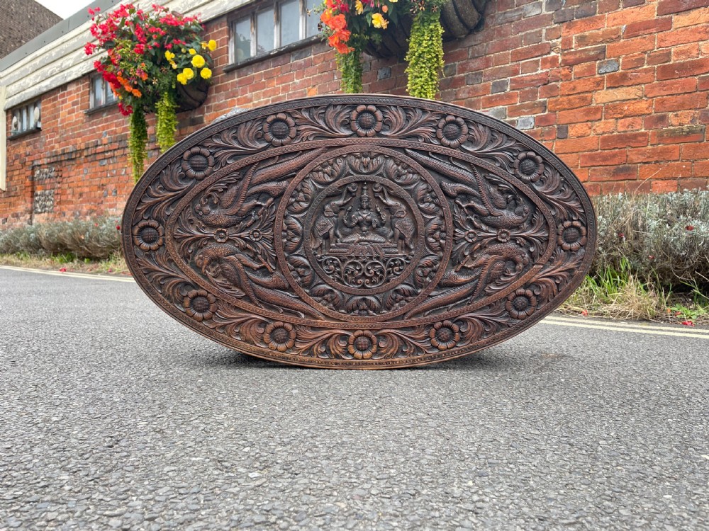 A circular dark carved wooden side table supported by three legs shaped like detailed elephant heads with trunks reaching to the floor. View IV