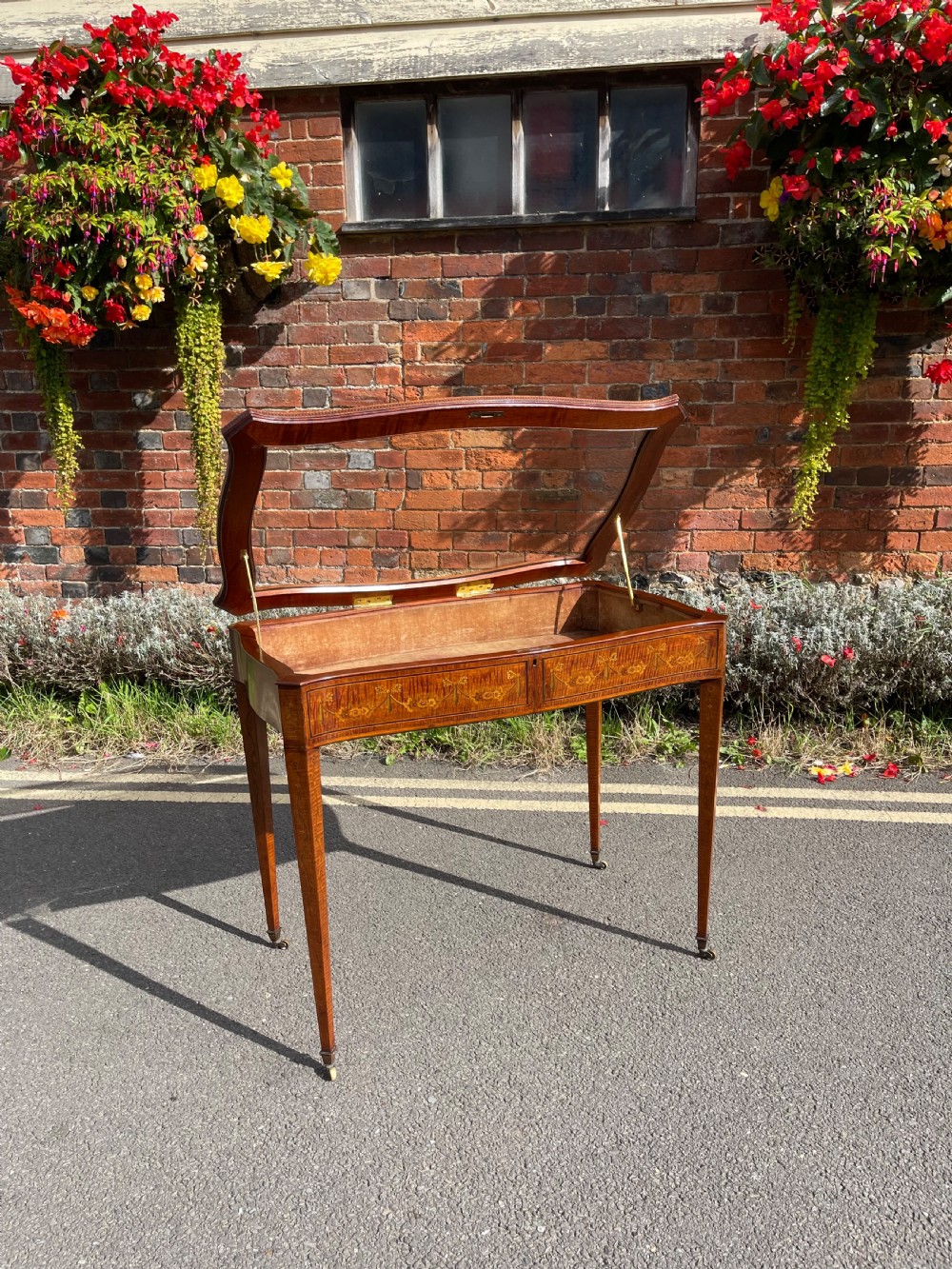 A late Victorian satinwood bijouterie table featuring a glazed display top, floral marquetry inlay along the frieze, and tapered legs with brass castors. View VII