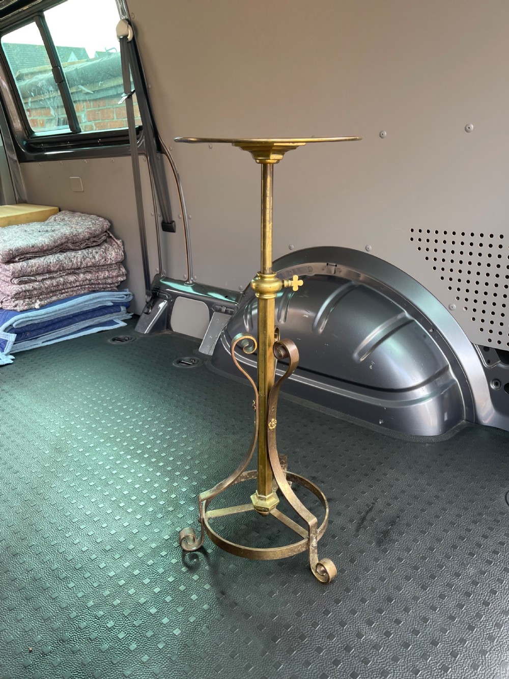 A nineteenth-century adjustable gilt brass standtable featuring a circular top, central column with a screw adjustment key, and scrolled tripod base.