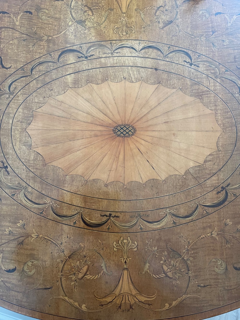 An oval antique mahogany Pembroke table with detailed marquetry inlay, drop leaves, and tapered legs. View III