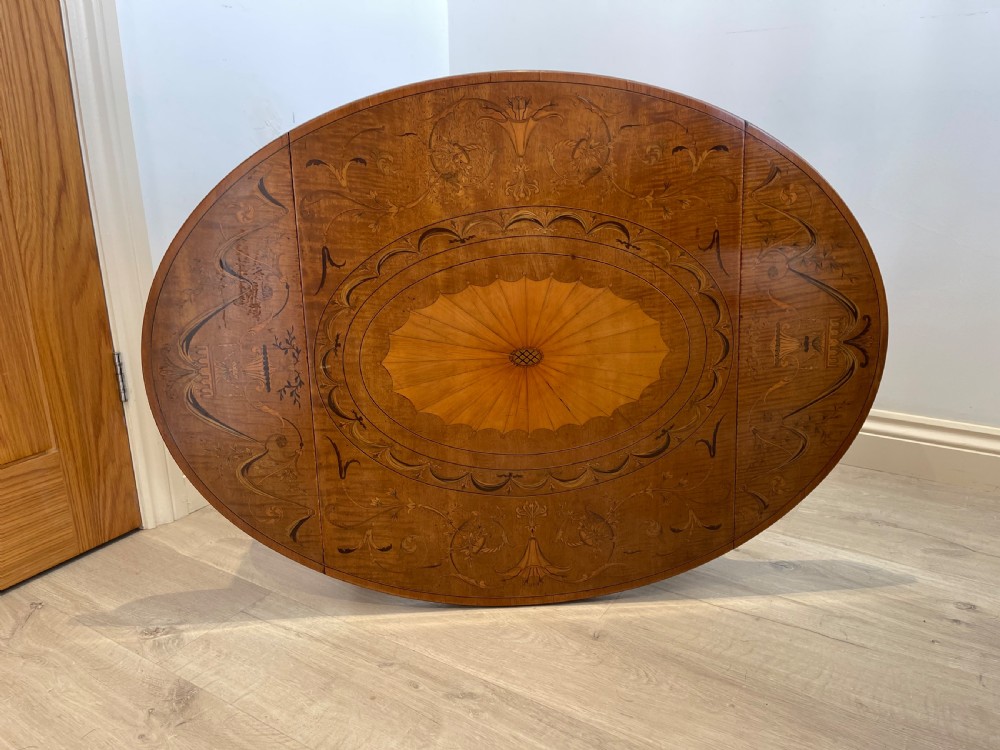 An oval antique mahogany Pembroke table with detailed marquetry inlay, drop leaves, and tapered legs. View VII