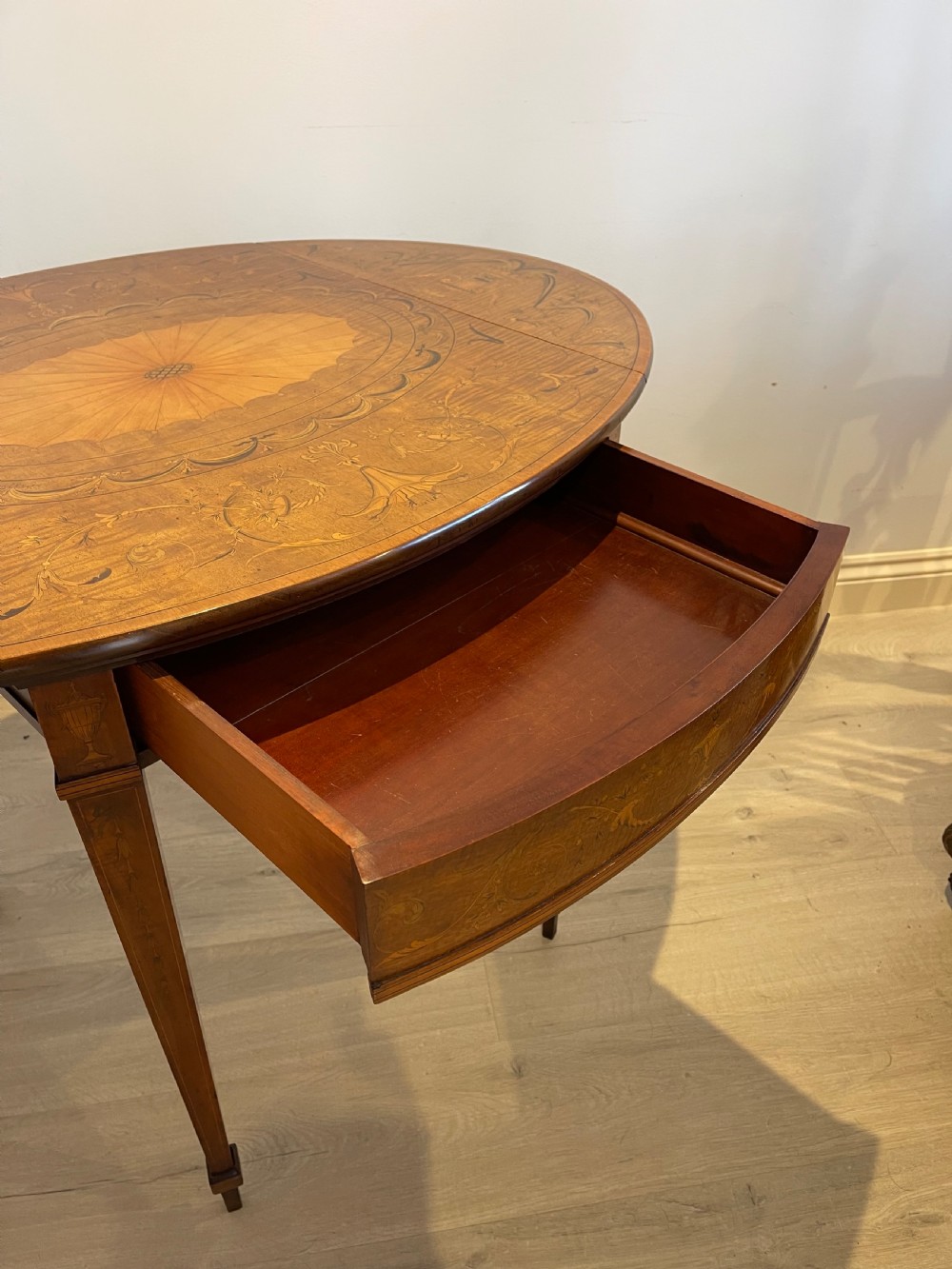 An oval antique mahogany Pembroke table with detailed marquetry inlay, drop leaves, and tapered legs. View X