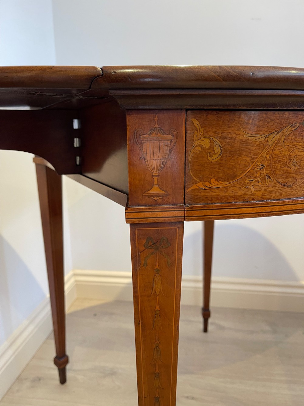 An oval antique mahogany Pembroke table with detailed marquetry inlay, drop leaves, and tapered legs. View XI